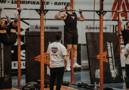Athletes performing pull-ups in a CrossFit competition, judged by officials, showcasing strength and endurance.