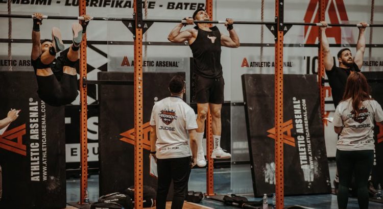 Athletes performing pull-ups in a CrossFit competition, judged by officials, showcasing strength and endurance.