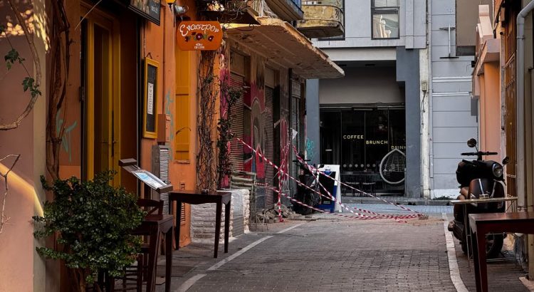 Explore a quaint alleyway in Athens, Greece, featuring inviting cafés and warm colors on a sunny day.
